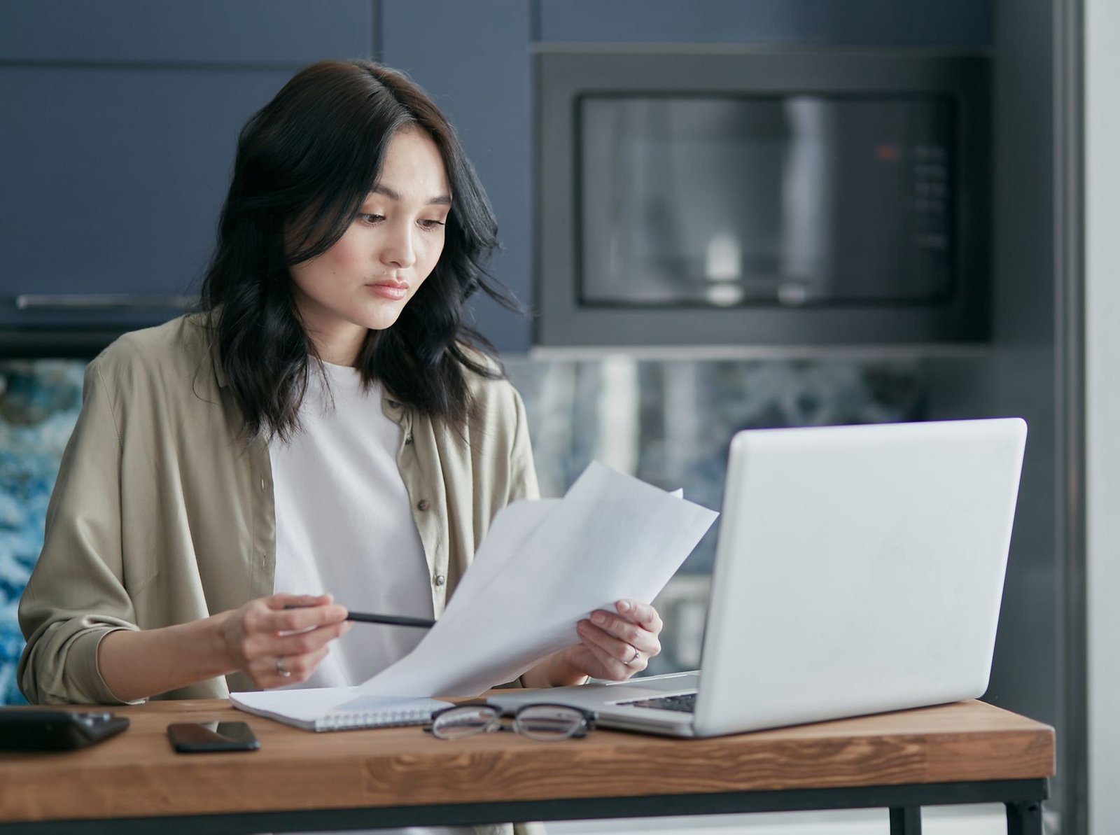 Person on the phone reviewing Medicaid mental health coverage paperwork at a kitchen table